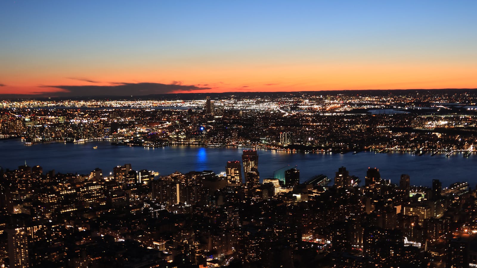 New York City at dusk, the skyline and rivers under a fading horizon.