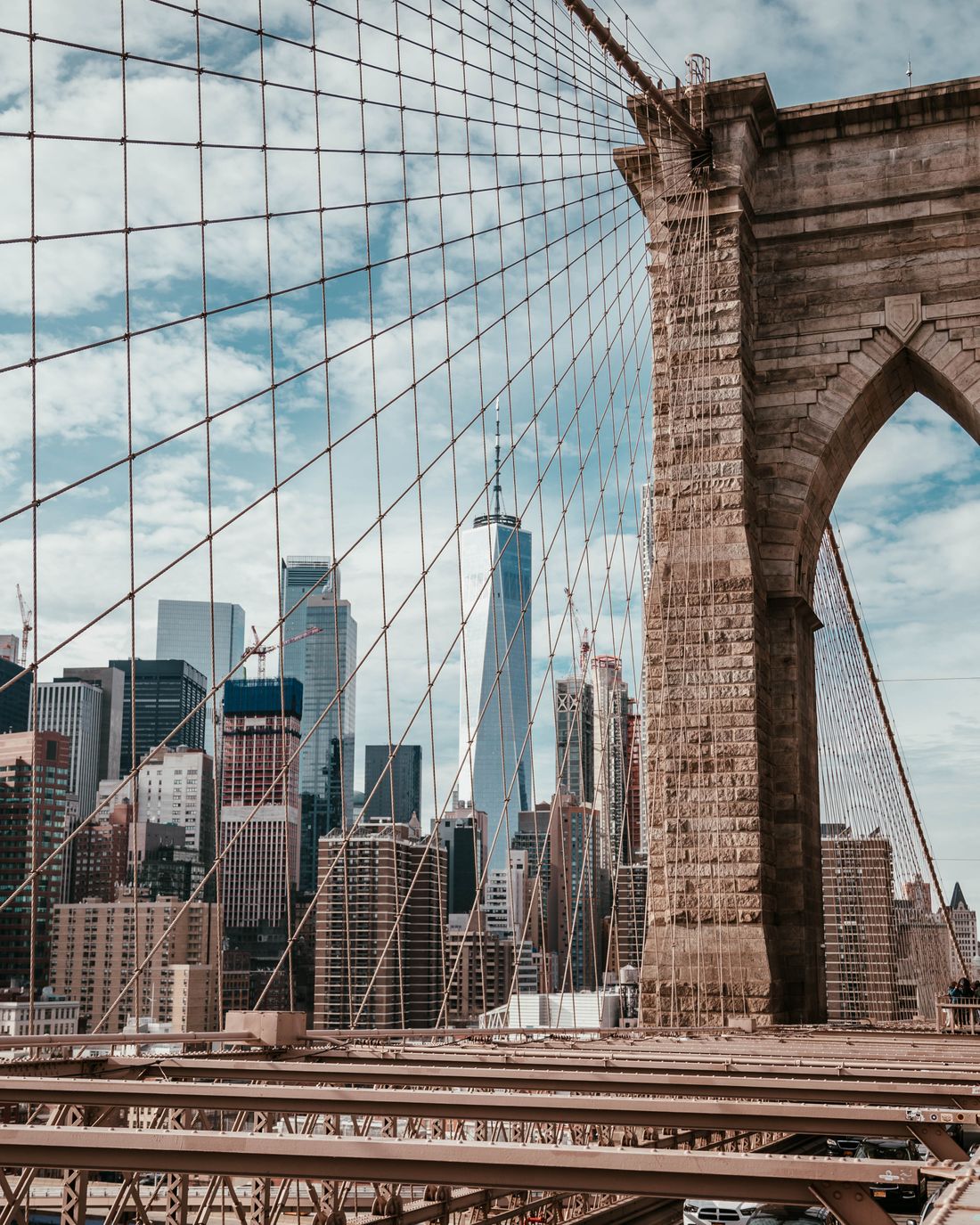 The Brooklyn Bridge arch and cables with the Lower Manhattan skyline behind.